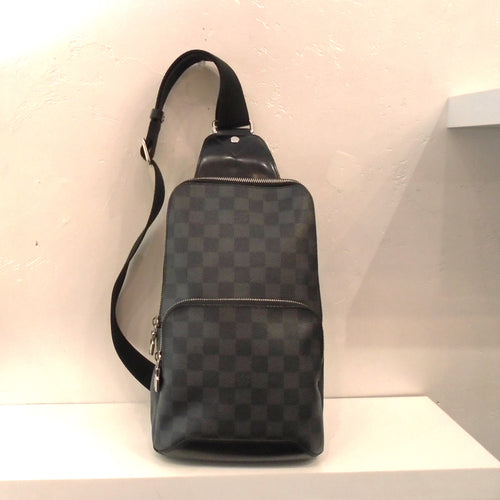 This Louis Vuitton  Vintage Damier Graphite Sling Bag has a top and middle zippered compartment and a sturdy canvas strap. It has two interchangable rings on the bottom for hooking the strap.