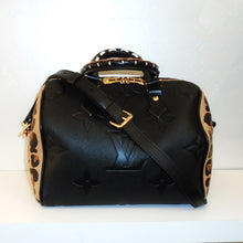 Load image into Gallery viewer, This Louis Vuitton Vintage Empreinte Leather Wild At Heart Speedy 25 has an adjustable and removable black shoulder strap. The front and back is in black empreinte leather and has the Louis Vuitton Monogram embossed in the leather. It has two carring handles on the top of the bag that are black with white stitch designs. The bag has a gold two headed zipper that meets at the top center of the bag. The sides have a leopard design on a light brown background.
