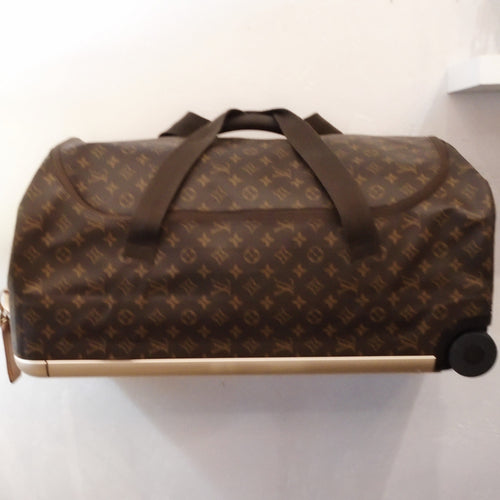 This Louis Vuitton Vintage Horizontal Soft Duffel #60 is in the brown monogram pattern. It has double handles on the side of the bag, a single handle on the top of the bag and two wheels on the bottom. It has a frame around the back of the suitcase for reinforcement. It also has a digital lock.