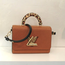 Load image into Gallery viewer, This Louis Vuitton Vintage Leopard Print Wild At Heart Collection Twist Top Handle bag is tan with a leopard print carrying handle which includes an attachable black shoulder strap. It has the Louis Vuitton logo in gold on the front flap of the bag. The interior of this bag is a soft black.
