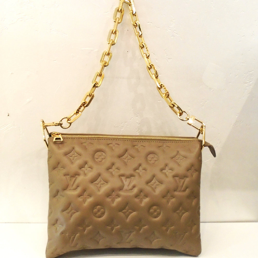 This Louis Vuitton Vintage Lambskin Taupe Coussin PM is embossed with the monogram pattern. It comes with  a heavy large link gold detachable shoulder chain and a Louis Vuitton Guitar Strap.  This bag also has its original box and dust cover. The interior of this bag is a soft navy blue. 