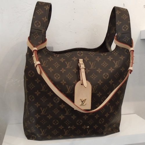 This Louis Vuitton Vintage Monogram Atlantis GM is in the original monogram and has wide shoulder handles on both sides at top of the bag. The shoulder handles are made from the same material at the rest of the bag. It has a key holder and additional strap in a cream tan color. The interior of the bag is camel and is open with no pockets.