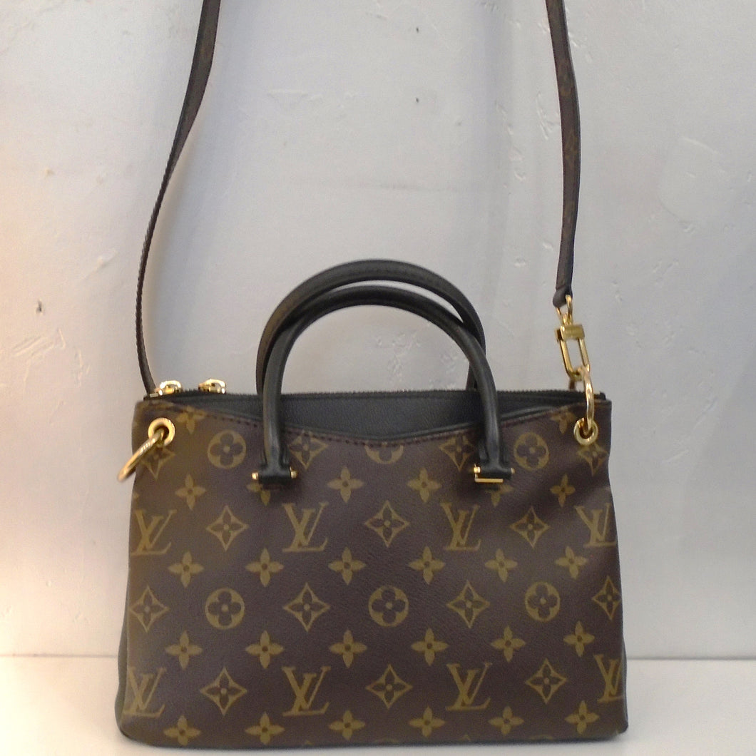 This Louis Vuitton Vintage Monogram/Black Pallas BB is a black leather bag with original monogram on both sides of the bag leaving the sides showing the black bag. It has two carrying handles and a long detachable shoulder strap included. The bag has gold hardware and a black interior.