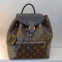 Load image into Gallery viewer, This Louis Vuitton Monogram/Black Montsouirs NMPM has the original monogram pattern on the body of the bag. It has a front lower zippered pocket and a black top flap that buckles. This Back Back has narrow sturdy back straps with a sturdy black loop for hanging. The interior of this backpack is red.
