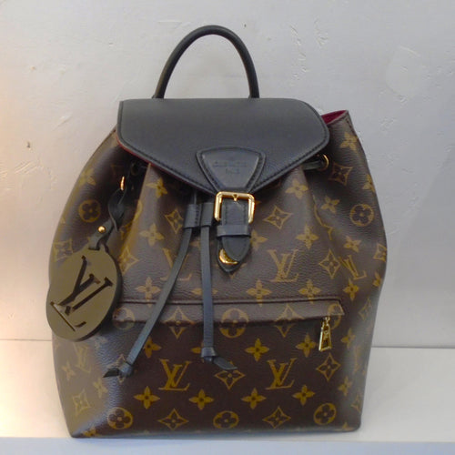 This Louis Vuitton Monogram/Black Montsouirs NMPM has the original monogram pattern on the body of the bag. It has a front lower zippered pocket and a black top flap that buckles. This Back Back has narrow sturdy back straps with a sturdy black loop for hanging. The interior of this backpack is red.