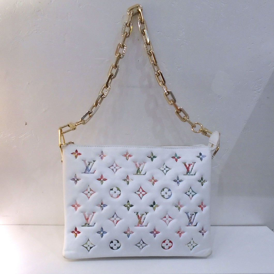 This Louis Vuitton Vintage Monogram Coussin Garden Collection has a white background with Spring colored monogram. It has a heavy detachable gold shoulder chain and guitar strap. This bag has a top zipper and lavender interior.