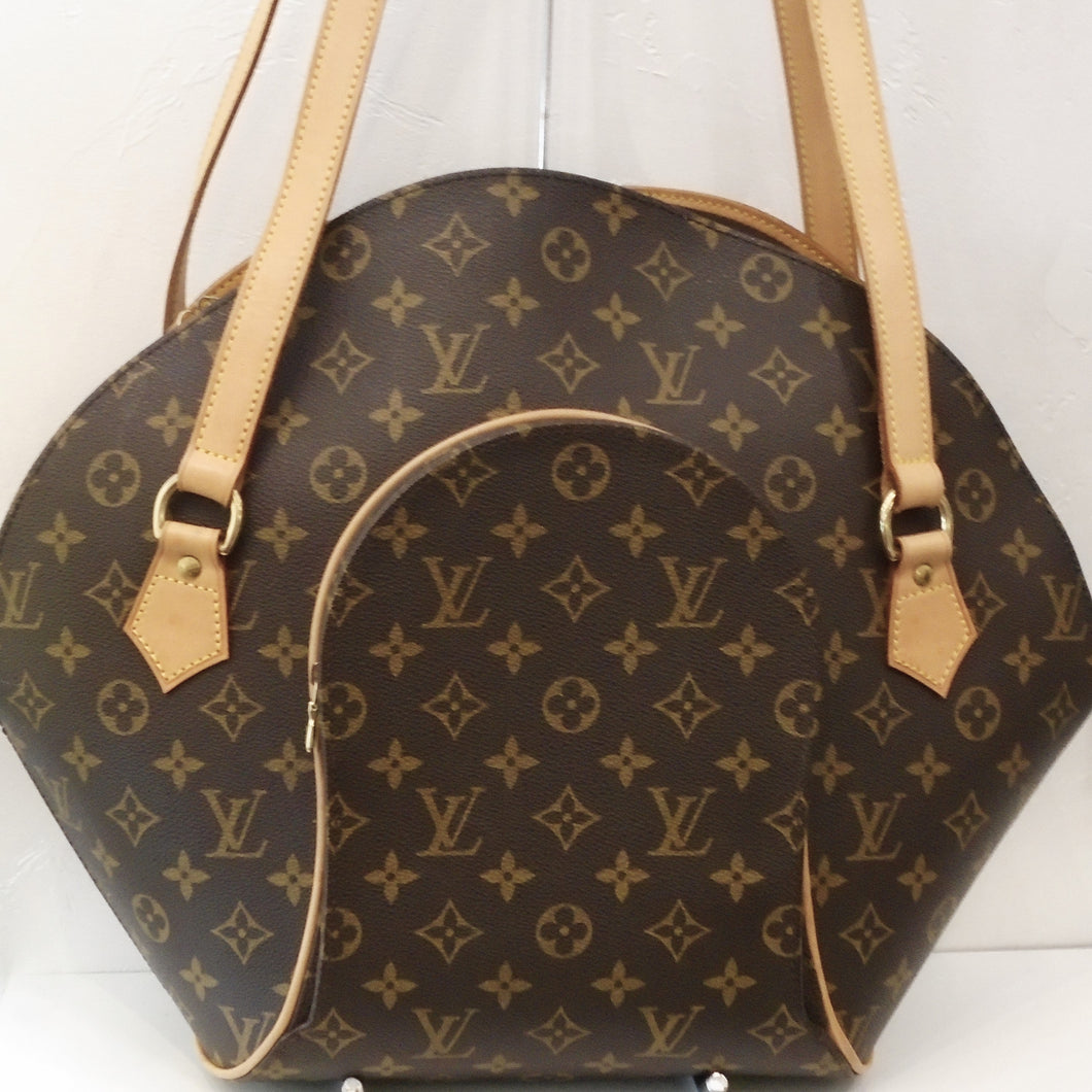 This Louis Vuitton Vintage Monogram Ellipse GM  has a front half moon zipper and a top zipper for easy access. It has camel trim and gold hardware. The interior of the bag is a dark camel  color.