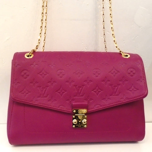 This Louis Vuitton Vintage Empreinte Saint Germain MM is a red-plum color and the flap has the monogram pattern embossed in the leather. The remainder of the bag is smooth leather. It has gold hardware which includes a shoulder chain and the front clasp. The design of the front clasp has a triangle that fits between two posts, one of which is stable. The interior of this bag is a soft plum color.