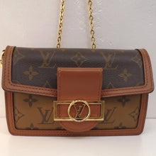 Load image into Gallery viewer, This Louis Vuitton Vintage Mini Feuille Dauphine has a dark background flap with light colored monogram that buckles over a light colored body with dark colored monogram. The latch is a rectangle with a circle in the middle and the Louis Vuitton Logo in the center of the circle in gold hardware. It has a gold shoulder chain and the interior is black.
