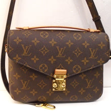 Load image into Gallery viewer, This Louis Vuitton Vintage Monogram Metis Pochette MM is in the original dark brown monogram style. It has a camel carrying strap on the top of the bag. A detachable shoulder strap which extends to a crossbody strap is included with this bag. It has a zippered pocket on the back and has two sections in the interior of the bag. This bag has gold hardware.
