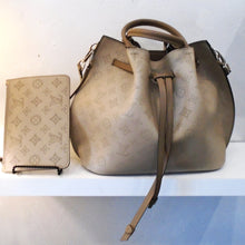 Load image into Gallery viewer, This Louis Vuitton Vintage Mahina Girolata With Pochette is a large drawstring bag with dark camel leather strips knotted at the ends for the drawstring. It has double handles, also in the dark camel leather. The bag is a light brown background with monogram print in a little darker brown.  The interior of the bag is a grey-brown with monogram pattern and Louis Vuitton printed on the bottom of the bag.
