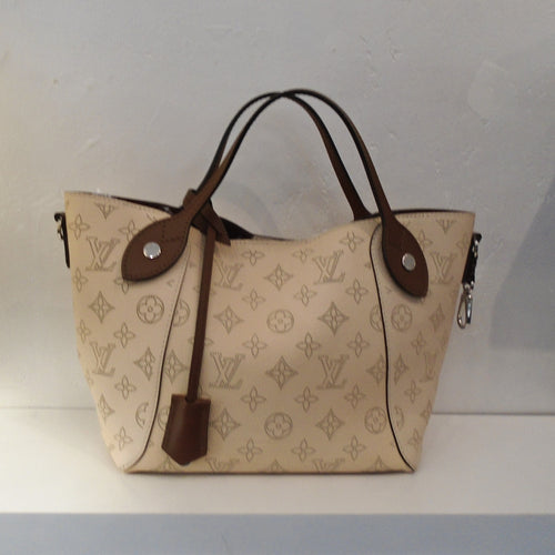 This Louis Vuitton Vintage Mahina Hina PM is beige with large beige monogram and dark brown trim which includes the carrying handles.  The interior is dark brown with a white bottom. It also has a detachable shoulder strap.