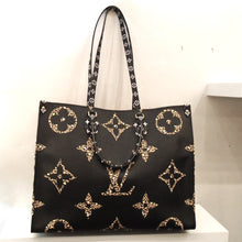 Load image into Gallery viewer, This Louis Vuitton Vintage Monogram Jungle On The Go GM has four different sides, each of which have cheetah and tiger motifs in the monogram. One side of this bag has a black background and the other side is a camel tan. The interior of this bag is camel tan with black stripes. The carrying handles are black with white monogram pattern.
