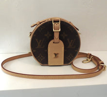 Load image into Gallery viewer, This Louis Vuitton Vintage Monogram Mini Boite Chapeau is a small circular bag with original Louis Vuitton monogram, a shoulder strap, a circular zipper opening and a short handle. All the trim, including the shoulder strap is in camel. It also has a key holder with the Louis Vuitton Logo on it. The interior of this bag is beige with a separated section.
