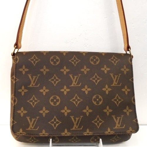 This Louis Vuitton Vintage Monogram Musette Tango Shoulder Bag is in the original brown tone monogram pattern. It has gold hardware and camel trim. It has an adjustable buckle shoulder strap and a deep brown interior.