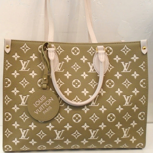 This Louis Vuitton Vintage Monogram On The Go MM Bicolor appears to be a Khaki Brown with cream small monogram and cream carrying handles. It has a key ring attached to the handle with 