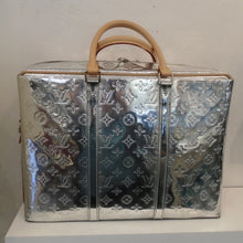 Load image into Gallery viewer, This Louis Vuitton Vintage Mirror Porte Documan Voyage Brief Case is a shiny silver with small Louis Vuitton monogram imprinted in the body of the bag. It has two carrying handles which are camel colored and includes a camel shoulder strap. The interior of the bag is a soft silver.
