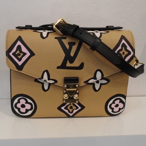 This Louis Vuitton Vintage Metis Pochette Giant Monogram Wild At Heart Arizona has a light tan background on the front and back, a black shoulder strap and gold hardware. It also has a white background on the sides of the bag and a back outside zipper. The interior of this bag is black.