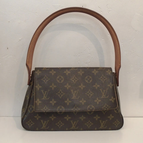This Louis Vuitton Vintage Monogram Shoulder Loop is in the original monogram pattern. It has a loop carrying handle large enough to wear as a shoulder bag. It has a front flap that reaches three quarters from the bottom of the bag. The interior of this bag is camel.