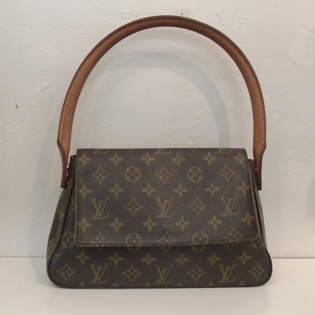 This Louis Vuitton Vintage Monogram Shoulder Loop is in the original monogram pattern. It has a loop carrying handle large enough to wear as a shoulder bag. It has a front flap that reaches three quarters from the bottom of the bag. The interior of this bag is camel.