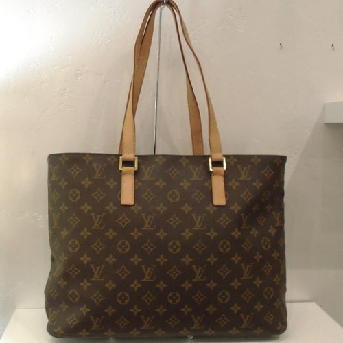 This Louis Vuitton Vintage Monogram Tote Bag has camel trim and gold hardware. It has a top zippered opening and a zippered pocket inside the bag. The interior of the bag is a soft beige.