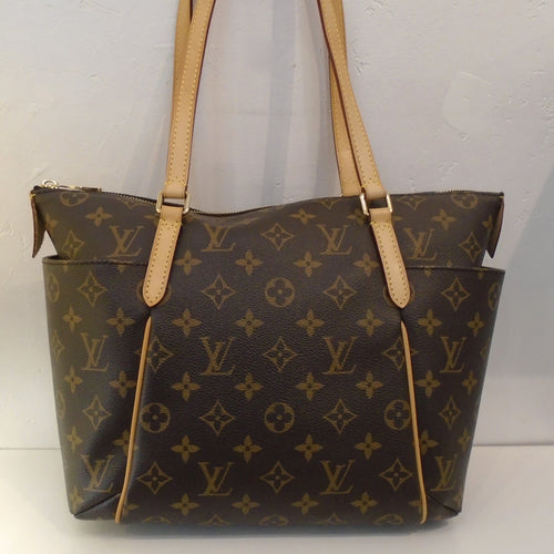 This Louis Vuitton Monogram Totally PM is in the original monogram pattern with camel trim. It has double shoulder straps with pockets on each side. The top zipper opens up to a dark camel interior.