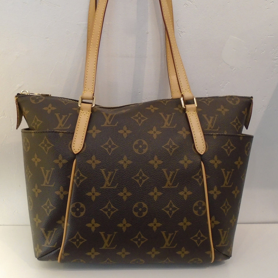 This Louis Vuitton Monogram Totally PM is in the original monogram pattern with camel trim. It has double shoulder straps with pockets on each side. The top zipper opens up to a dark camel interior.