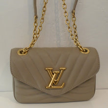 Load image into Gallery viewer, This Louis Vuitton Vintage New Wave Flap Crossbody is beige with the wave stitching. It has a front flap that starts on the sides midway of the bag and tapers down to the bottom middle. The gold shoulder chain has a beige shoulder guard and the Louis Vuitton logo is on the front lip of the the flap in gold. The interior of this bag is also beige.
