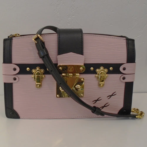 This Louis Vuitton Vintage Pink Epi Trunk Clutch is made to have the appearance of a trunk. It has gold hardware resembling  trunk latches. The trim on this clutch is black and has three XS in the right lower corner. It also has a detachable shoulder strap and the interior is pink.