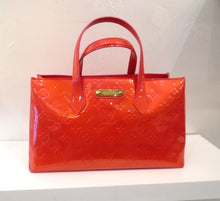 Load image into Gallery viewer, This Louis Vuitton Vintage Red Vernis Leather bag has the monogram pattern imprinted on the bag. It has double handles and a gold Louis Vuitton name plate on the front of the bag. The interior of the bag is a pink shade and has a hook and latch inside the bag to keep the top of the bag closed.
