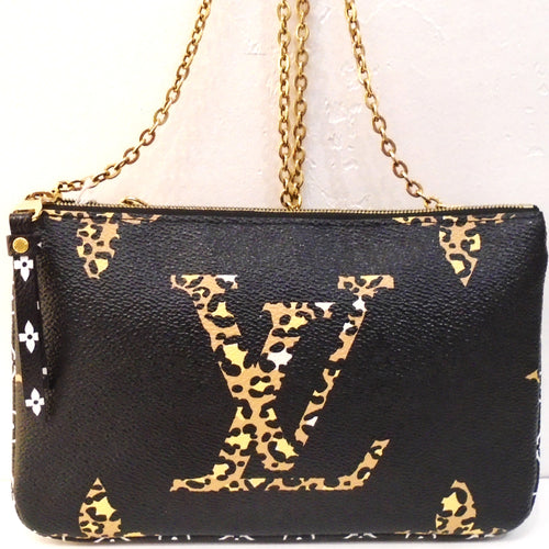 This Louis Vuitton Vintage Reverse Jungle Double Pochette Crossbody has gold hardware and two different sides. One side has a black background with large monogram in lepord. The other side has smaller white monogram against a background of light and dark camel tiger stripes. The inside has a zippered pocket which has both designs and a cardholder that is black with white monogram.