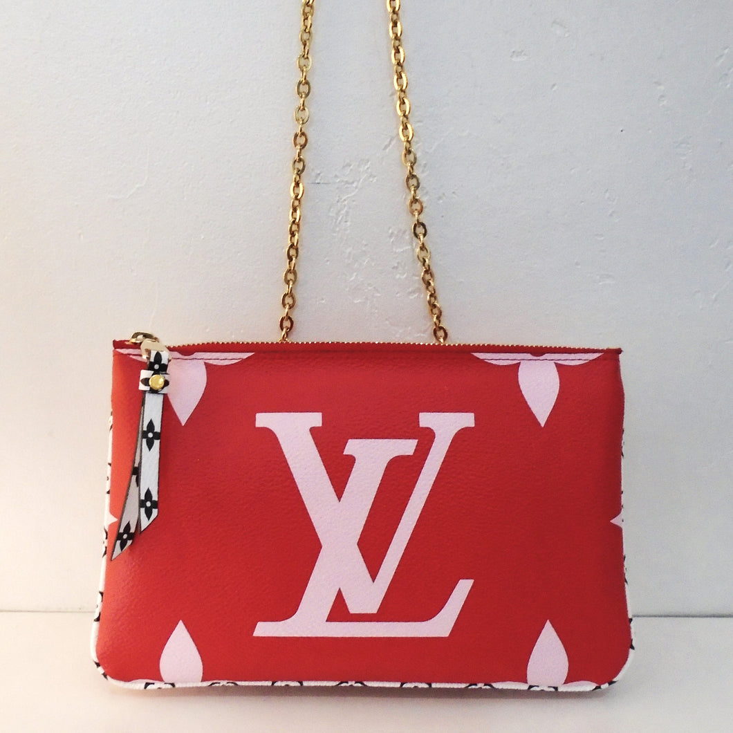 This Louis Vuitton Vintage Reverse Pochette Double Zip is red with large monogram design in white on the front side. It is pink with small white monogram on the other side. It is two pochetts attached together and has black and white trim. The leather strips attached to the zipper are also black and white. This bag has gold hardware and  the interior is pink.