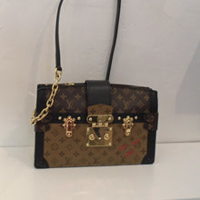 Load image into Gallery viewer, This Louis Vuitton Reverse Trunk Clutch has the original monogram design with both the original dark and light backgrounds. It has gold hardware and a shoulder strap. The bag has a top zipper with a strap which crosses the top and latches to the front latch. There is a top zipper which opens to a divided interior which is a light brown.
