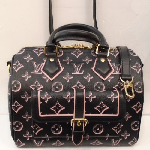 This Louis Vuitton Vintage Speedy 30 is black with a pink monogram pattern. The trim is black with some pink outlining. It comes with a black detachable adjustable shoulder strap. This bag has gold hardware and a pink interior.  It has a buckled pocket on the front of the bag.