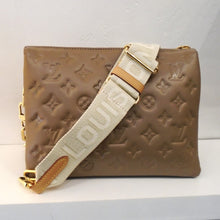 Load image into Gallery viewer, This Louis Vuitton Vintage Lambskin Embossed Monogram Coussin PM is taupe with gold  hardware. It includes a louis vuitton guitar strap with gold hardware and camel leather. It has a removable shoulder chain and blue interior.
