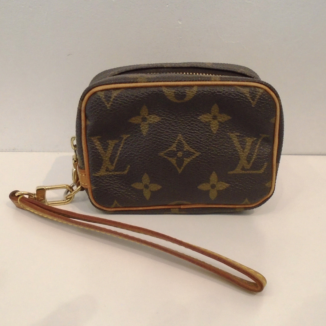 This Louis Vuitton Trousse Wapity Wristlet is small enough to fit in your hand. It has camel trim which includes the wrist loop. The pattern on this Wristlet is in the original large monogram. The interior of this Wristlet is red.