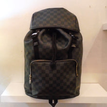 Load image into Gallery viewer, This Louis Vuitton Vintage Zack Backpack Black Graphite Ebene has gold hardware and two strudy back straps that cross. It has two inside buckles for extra security, a gathered top and a cover that pulls down over the top of the bag. There is a large zippered pocket on the front of the bag. It also has a sturdy loop on the bottom of the bag for hanging on a hook.
