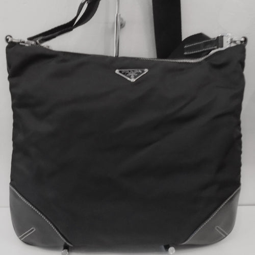 This Prada Vintage Large Nylon Top Zip Messenger has silver hardware and leather corner reinforcements. It has an adjustable canvas shoulder strap. The interior of the bag is black with Prada written in silver on the inside of the bag.