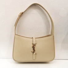 Load image into Gallery viewer, This YSL Cream Hobo Bag is a dark cream color with a thick adjustable shoulder strap. The top opening of the bag closes with a leather strip attached from the back to the front by a YSL logo hook into a bottom leather piece. The interior of the bag is the leather underside of the bag.
