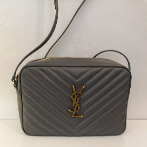 This YSL Loulou Dark Grey Camera Bag has the Chevron design. It has gold hardware which includes the YSL logo on the front of the bag. This bag has an outside back pocket and the interior is black.