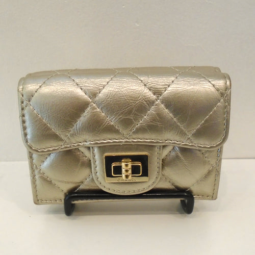This is a small hand held gold tone wallet with diamond design stitching. It has a gold clasp on the front and opens up to hold essentials.
