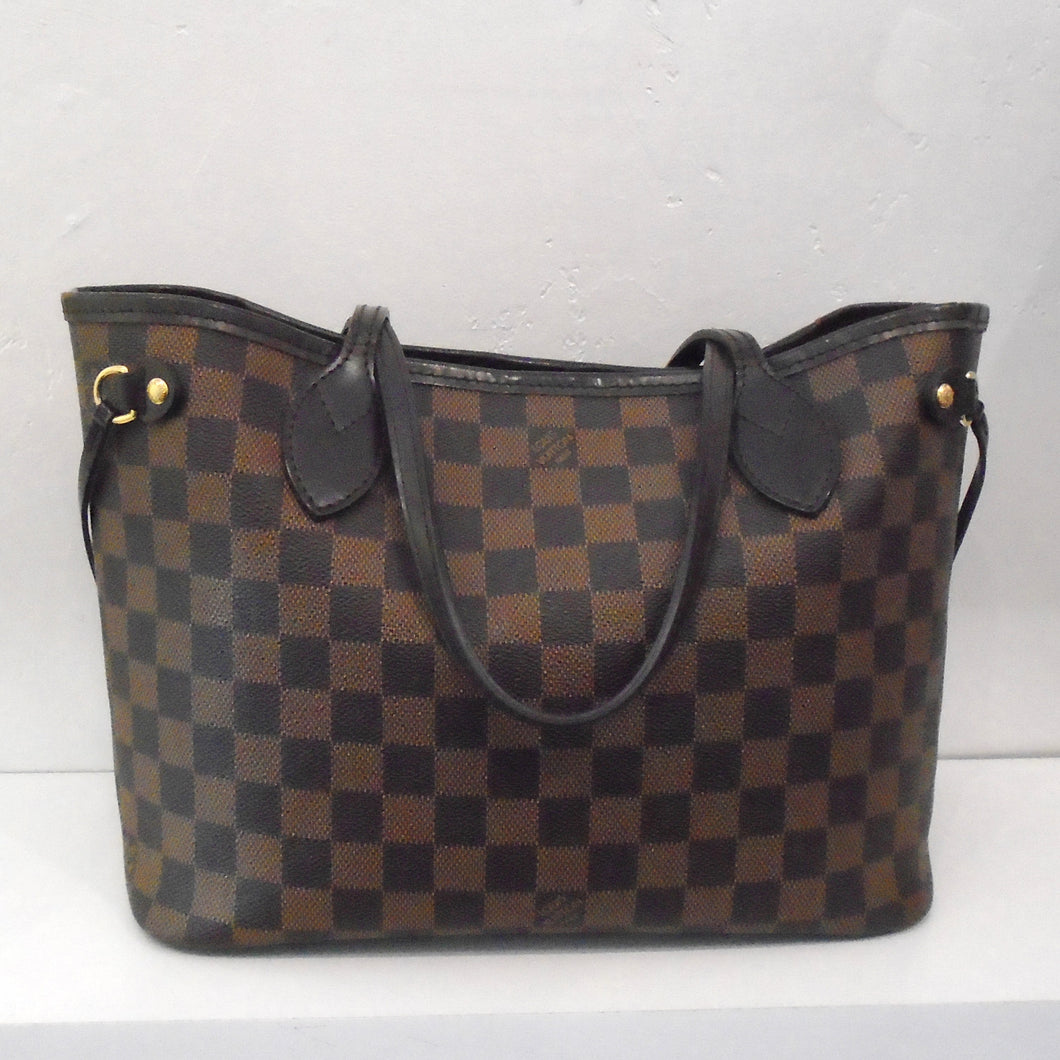 This Louis Vuitton Vintage Neverfull PM Damier Ebene tote has dark brown leather handles on top and side ties. It has a lined red interior.