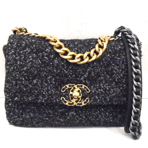 This Chanel Vintage Black/Blue Charcoal Boucle bag is a woven material with black, blue and charcoal colors. It has two gold interlocking C's as a clasp with a thin black leather strip woven in the C's. The bag has a gold shoulder chain with a black leather shoulder guard. The guard has a silver chain on the top of it with a black leather strip woven in the chain. The inside of the bag is the same material as the outside of the bag with a black bottom.