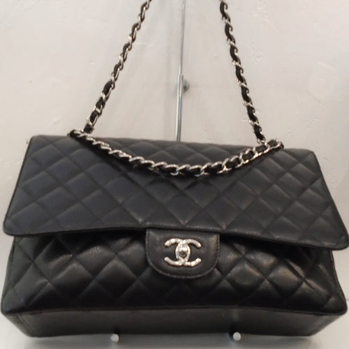 This Chanel Vintage Black Caviar Maxi with Silver Hardware is in the traditional diamond stitch pattern with the Chanel CC on the front twist clasp. The silver shoulder chain has a black leather strip running through it. The bag has a large pocket on the back.
