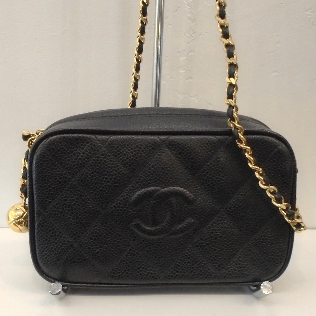 This Chanel Vintage Caviar Leather Micro Mini Bag has gold hardware and a top zippered opening. The gold shoulder chain has a black leather strip woven between the gold chain links. The bag is in the quilted diamond pattern with embroidered Chanel CCs on the front center of the bag.