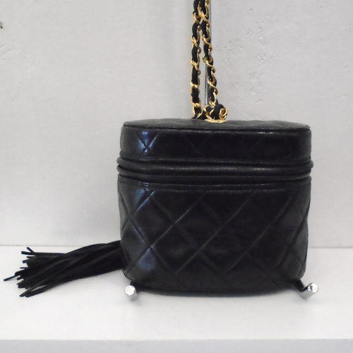 This Chanel Matelasse Labmskin Bag w/Tassel is in Black Lambskin with a zipper that reaches from back around front and back again to give it a top opening. The bag itself is a short barrel style bag. It has a tassel at the end of the zipper, the tassel itself being made of leather strips. It has a gold shoulder chain with a black leather piece interwoven between the chain links.