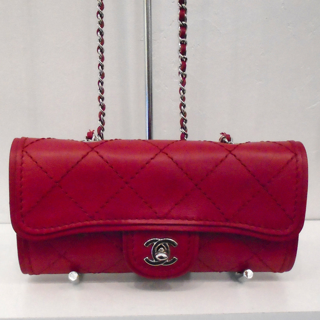 This Chanel Vintage Ultimate Stitch WOC is made of lambskin leather that is a in a sangria red color. It has silver hardware which includes the double C logo clasp and shoulder chain. A sangria red leather shoulder guard is included on the chain along with a leather strip threaded between the links of the shoulder chain. There is a pocket on the back of the bag made of the same material as the bag.