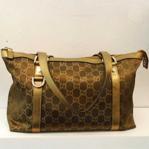 This Gucci Vintage Gold Canvas GG Abbey Tote has the Gucci logo design on the bag with Gold straps coming up either side of the bag. It has gold double carring strap handles and silver hardware.