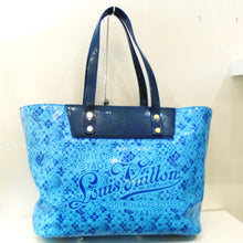 Load image into Gallery viewer, This Louis Vuitton Vintage 2 Tone Cosmic Blossom Tote is in a lovely shade of baby blue with navy trim. Its pattern is a variation of flowers, diamonds and smiley faces. It has the name Louis Vuitton on the front of the bag with the phrase Articles of Voyage along with a Paris address. The inside of the bag is also in a baby blue shade.
