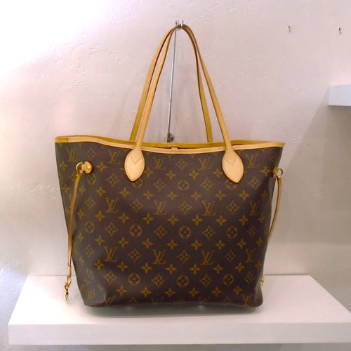 This Louis Vuitton Vintage Monogram Neverfull MM is in the traditional brown monogram pattern with camel trim. It has leather side laces to help secure the opening. This bag is lined with a soft brown fabric.